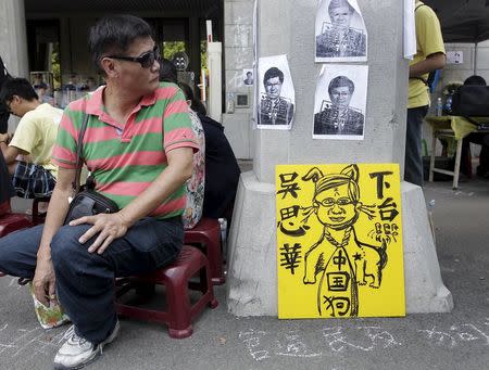 An activist looks at the papers with Taiwan's Education Minister Wu Se-hwa's picture during a protest at the entrance to the Ministry of Education in Taipei, Taiwan, August 1, 2015. REUTERS/Pichi Chuang