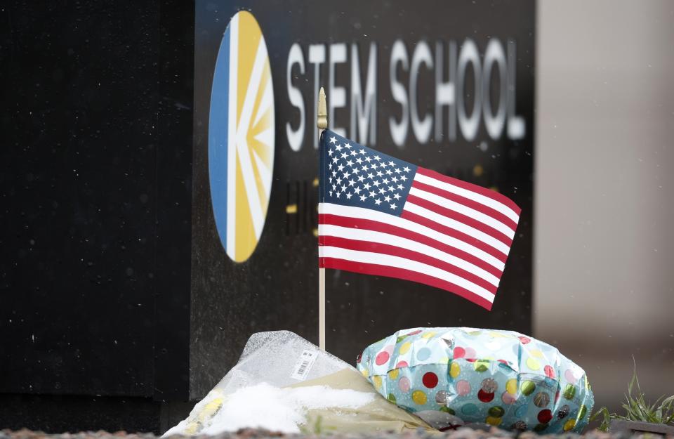 An American flag unfurls in the wind in a small tribute placed below the sign for STEM School Highlands Ranch following Tuesday's shooting, in Highlands Ranch, Colo., Thursday, May 9, 2019. (AP Photo/David Zalubowski)