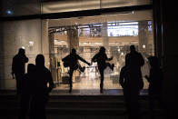 Protesters break the windows of a commerce during clashes following a protest condemning the arrest of rap singer Pablo Hasél in Barcelona, Spain, Saturday, Feb. 27, 2021. Protests in support of a jailed rapper turned violent in Barcelona on Saturday with clashes between police and groups of mostly angry youths in the center of the Spanish city. (AP Photo/Emilio Morenatti)