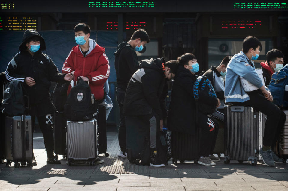 People wearing masks with their suitcases.