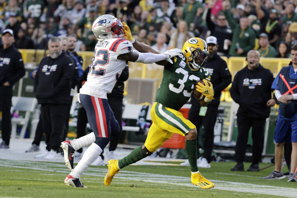 Green Bay Packers running back Aaron Jones (33) tries to break a tackle by New England Patriots safety Devin McCourty (32) during the second half of an NFL football game, Sunday, Oct. 2, 2022, in Green Bay, Wis. (AP Photo/Mike Roemer)