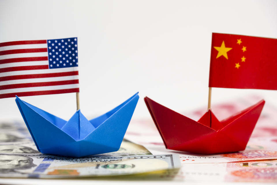 US America flag on blue ship and China flag on red ship and multi color flag with white background of war trade which they counteract by increase import and export tax barrier and effect world economy