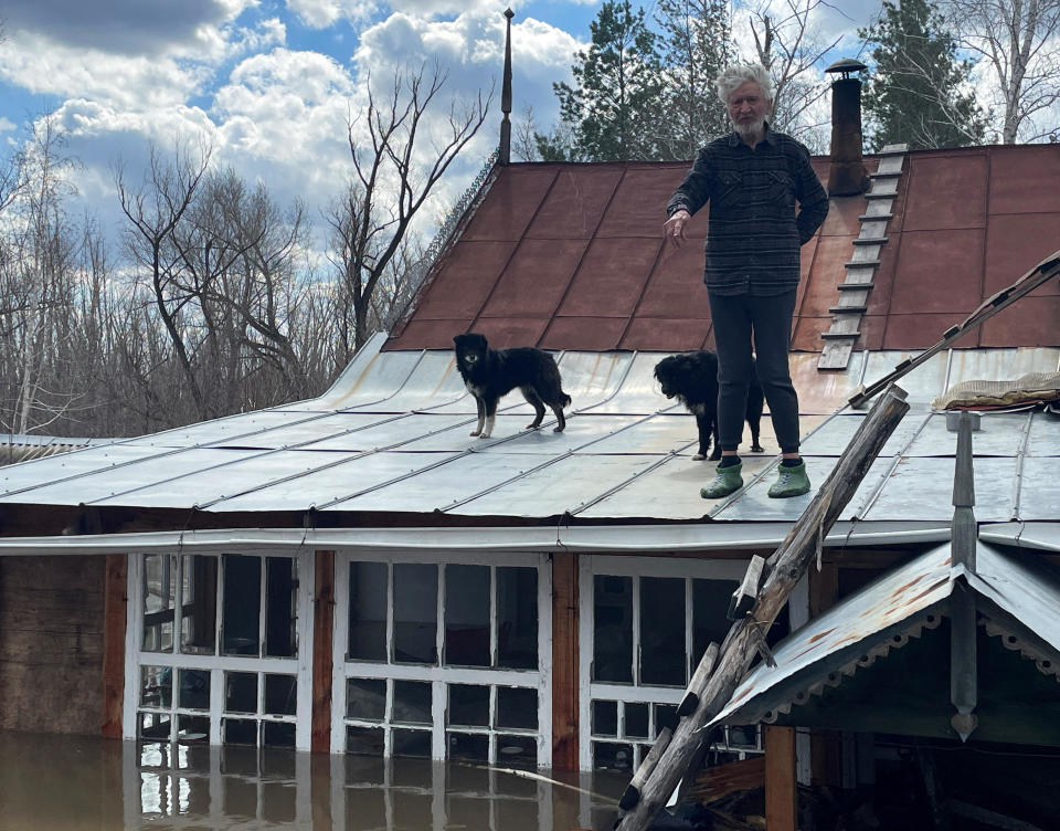 Artist Nikolai Kryuchkov stands on the roof of his flooded house in Orenburg, Russia, April 13, 2024. / Credit: Alexander Reshetnikov/REUTERS