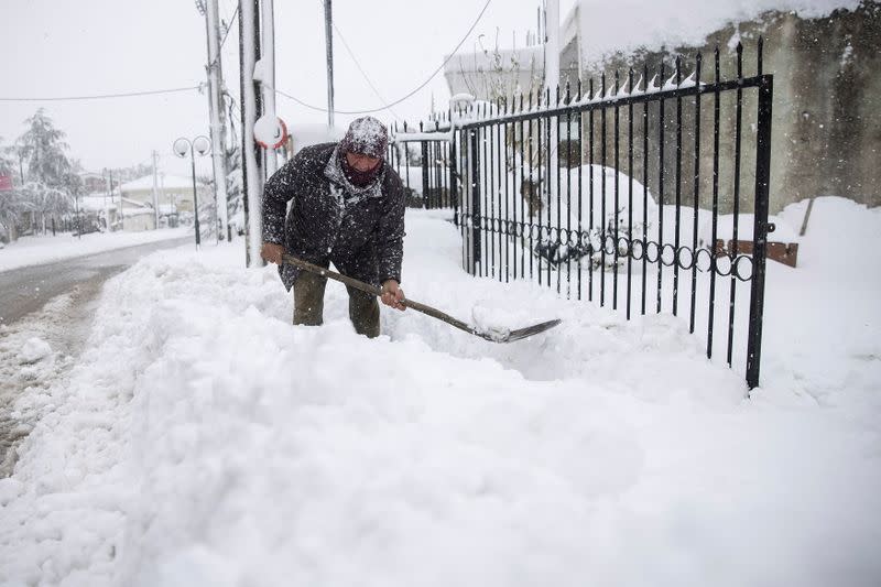 Panagiotis Economou quita nieve desde la entrada de su propiedad durante las fuertes nevadas, en el pueblo de Kapandriti, Grecia, el 15 de febrero de 2021.