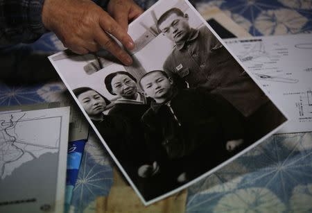 Japanese Katsumoto Saotome, 82, a survivor of Great Tokyo Air Raids in 1945, points to his family photo taken in 1943 during an interview with Reuters at his home in Tokyo March 4, 2015. REUTERS/Issei Kato