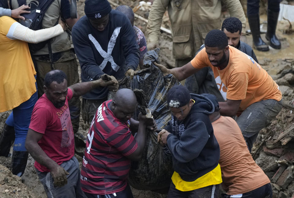Residents and volunteers remove the body of a mudslide victim in Petropolis, Brazil, Wednesday, Feb. 16, 2022. Extremely heavy rains set off mudslides and floods in a mountainous region of Rio de Janeiro state, killing multiple people, authorities reported. (AP Photo/Silvia Izquierdo)