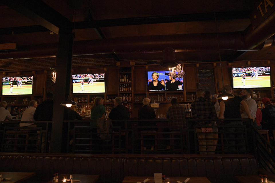 Patrons at the Hawk 'n' Dove sit in front of television screens televising Game 4 of the NLCS between Washington Nationals and the St. Louis Cardinals and a debate by Democratic presidential candidates, Tuesday, Oct. 15, 2019, in Washington. Tuesday night presents a quandary for many Washingtonians: the Democratic presidential debate on a night when the Washington Nationals have a chance to make it to their first-ever World Series. (AP Photo/Nick Wass)