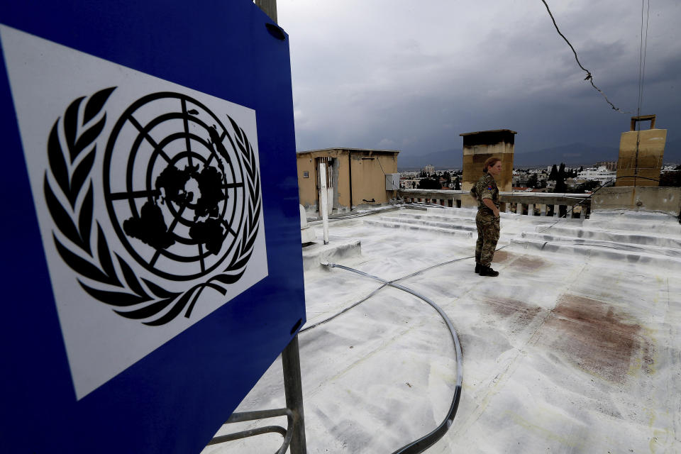 In this Friday, April 19, 2019, photo, a U.N. peacekeeper stands on the roof of the Ledra Palace hotel inside the U.N. buffer zone in the divided capital Nicosia, Cyprus. This grand hotel still manages to hold onto a flicker of its old majesty despite the mortal shell craters and bullet holes scarring its sandstone facade. Amid war in the summer of 1974 that cleaved Cyprus along ethnic lines, United Nations peacekeepers took over the Ledra Palace Hotel and instantly turned it into an emblem of the east Mediterranean island nation's division. (AP Photo/Petros Karadjias)
