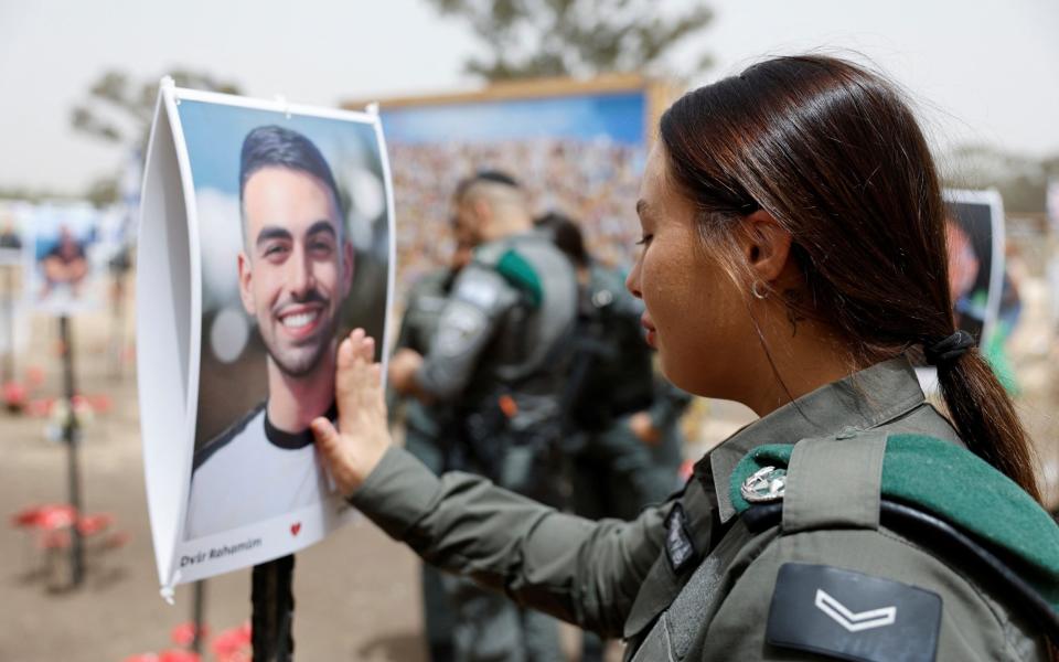 An Israeli border police officer touches a picture of her friend who died during the October 7 attack by Hamas gunmen from Gaza at the site of the Nova festival