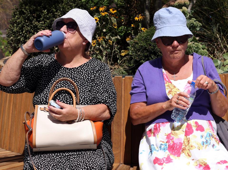 Women rest on a bench and drink water in Canary Wharf, London (Kevin Coombs/Reuters)