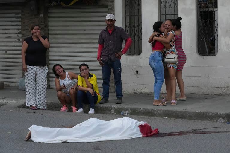 Varias personas lloran junto al cadáver de un hombre, asesinado en circunstancias desconocidas, en una calle de Durán, Ecuador, el 21 de julio de 2023, en medio de una ola de violencia que las autoridades atribuyen a la lucha de territorio entre bandas del crimen organizado. 