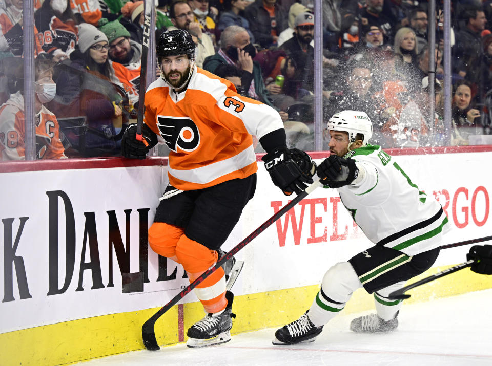 Philadelphia Flyers' Keith Yandle, left, and Dallas Stars' Luke Glendening battle along the boards during the first period of an NHL hockey game, Monday, Jan. 24, 2022, in Philadelphia. Yandle tied the NHL record for consecutive games played with 964 on Monday. (AP Photo/Derik Hamilton)