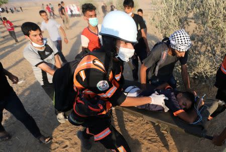 A wounded Palestinian is evacuated during a protest at the Israel-Gaza border in the southern Gaza Strip July 13, 2018. REUTERS/Ibraheem Abu Mustafa