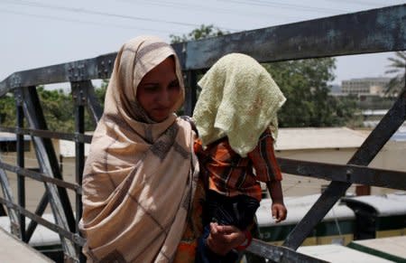 A mother holds her child, covered with a towel to avoid sunlight, during a heatwave in Karachi, Pakistan May 21, 2018. REUTERS/Akhtar Soomro