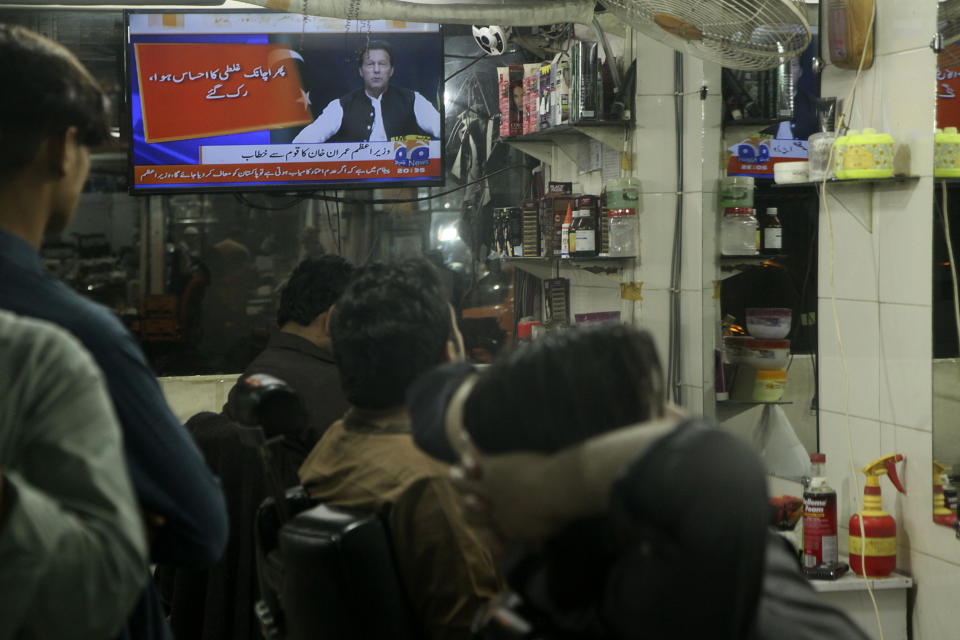 People watch a news channel broadcast a live address to the nation by Pakistan's Prime Minister Imran Khan at a barbershop, in Peshawar, Pakistan, Thursday, March 31, 2022. Pakistan's embattled Prime Minister Khan remained defiant on Thursday, telling the nation that he will not resign even as he faces a no-confidence vote in parliament and the country's opposition says it has the numbers to push him out. (AP Photo/Muhammad Sajjad)