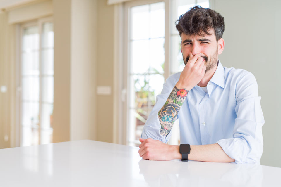 A man plugging his nose from a smell