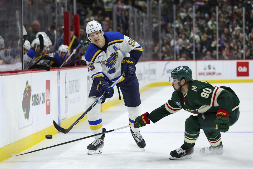 St. Louis Blues defenseman Colton Parayko, left, passes against Minnesota Wild left wing Marcus Johansson (90) during the second period of an NHL hockey game, Tuesday, Nov. 28, 2023, in St Paul, Minn. (AP Photo/Matt Krohn)