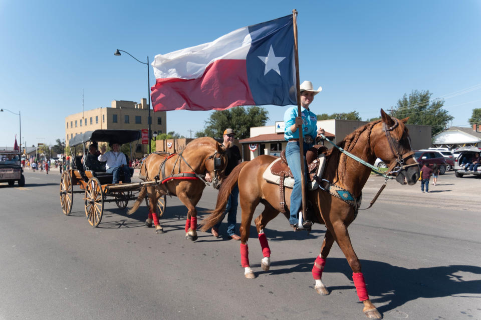 A wagon is led down Main Street by a flag bearing rider at the 104th annual Wheatheart of the Nation Parade Saturday in Perryton, Texas.