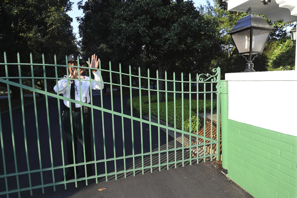 A guard at the main gate to Augusta National Golf Club on Magnolia Lane warns away visitors on what would have been the first practice round for the Masters golf tournament, Monday, April 6, 2020, in Augusta, Ga. The 2020 Masters, postponed because of the coronavirus pandemic, is slated to take place on Nov. 12-15. (Curtis Compton/Atlanta Journal-Constitution via AP)