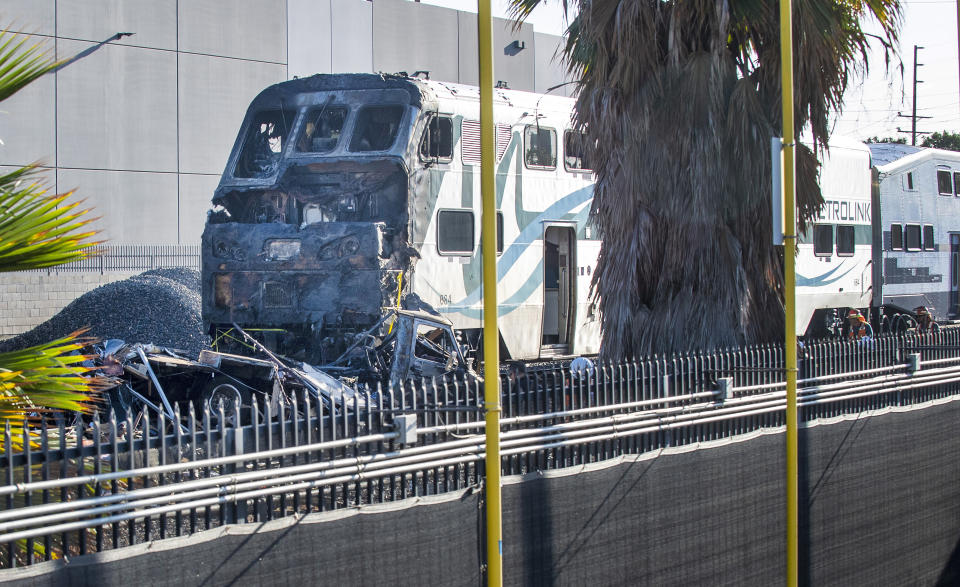 Investigators work at the scene after an RV was hit by a commuter train and burst into flames along a track in Santa Fe Springs, Calif., Friday, Nov. 22, 2019. Authorities say the collision occurred shortly after 5:30 a.m. Friday at an intersection in an industrial area of Santa Fe Springs. There were no immediate reports of injuries. All passengers on the Metrolink train were safely evacuated. (Mark Rightmire/The Orange County Register via AP)