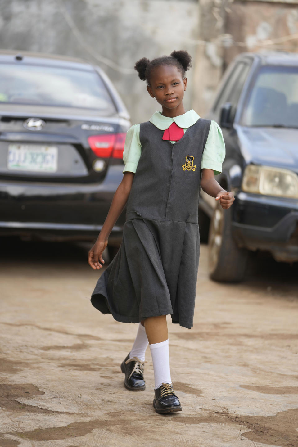 Princess Igbinosa, 10, who lost her leg following a traffic accident, models a school dress outside her parents' house in Lagos, Nigeria, Friday, Dec. 1, 2023. Princess can now walk, thanks to an artificial limb from the IREDE Foundation, a group providing children like her with free prosthetics and helping their families offset the average cost of $2,000 to $3,000.(AP Photo/Sunday Alamba)