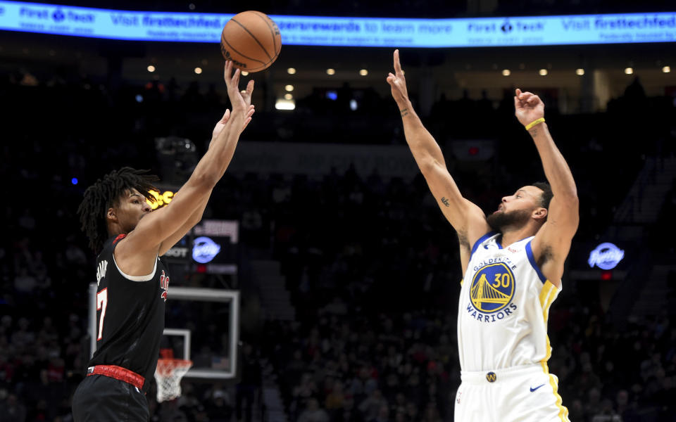 Portland Trail Blazers guard Shaedon Sharpe, left, shoots over Golden State Warriors guard Stephen Curry, right, during the first half of an NBA basketball game in Portland, Ore., Sunday, Dec. 17, 2023. (AP Photo/Steve Dykes)