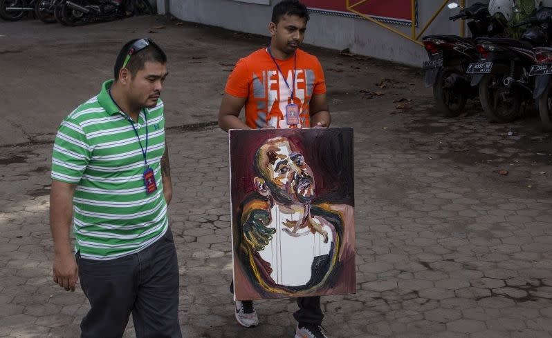 Michael Chan, left and Chinthu Sukumaran carry a self-portrait painting of Myuran Sukumaran. Picture: Getty Images