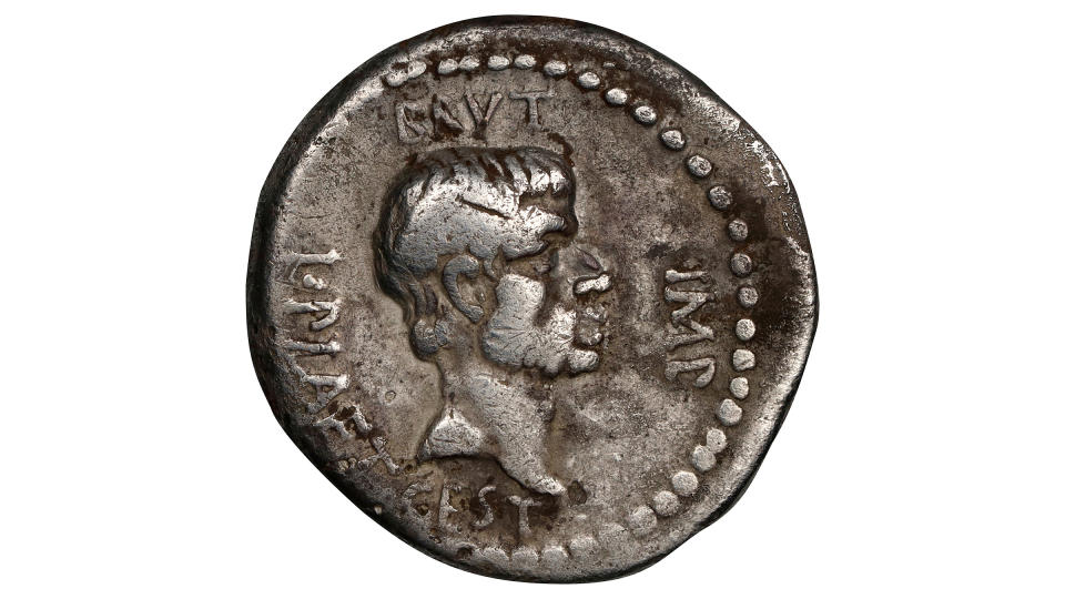 A silver coin against a white background. It has the profile of a man, Brutus.