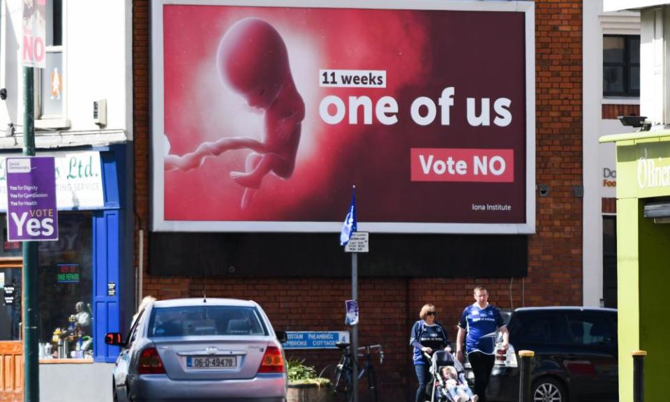 Pedestrians pass a billboard urging a no vote in the referendum to preserve the eighth amendment of the Irish constitution