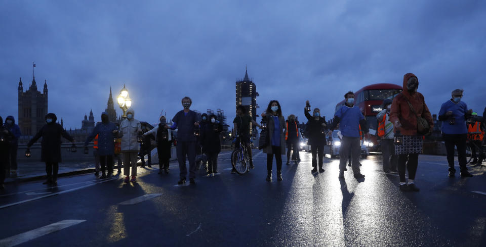 Campaigners hold lanterns on Westminster Bridge for British NHS medical and care workers who have died due to COVID-19, in London, Friday, July 3, 2020. A number of NHS staff and campaigners will carry one lantern to represent people who have died due to COVID-19, as they walk from St. Thomas' Hospital over Westminster Bridge to then hold a candlelit vigil outside Downing Street, where they read out a small number of representative names of NHS staff who died. (AP Photo/Alastair Grant)