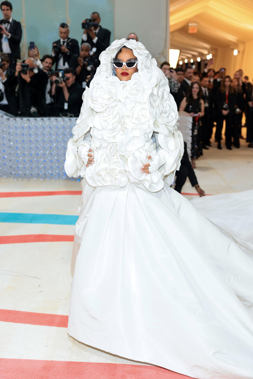 Rihanna attends the 2023 Met Gala in a white Maison Valentino gown with a floral hood