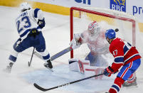Tampa Bay Lightning's Michael Eyssimont (23) scores against Montreal Canadiens goaltender Cayden Primeau, center, as Canadiens' Jayden Struble (47) defends during first-period NHL hockey game action in Montreal, Thursday, April 4, 2024. (Graham Hughes/The Canadian Press via AP)