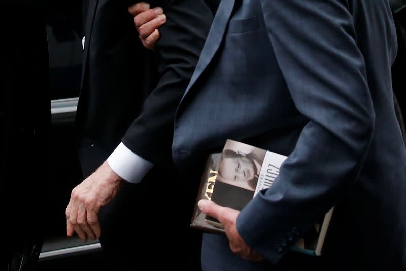 Man holds books as he escorts film producer Harvey Weinstein to his car in New York