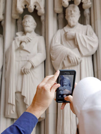 A passerby takes a photograph of the defaced statue of Confederate commander General Robert E. Lee, at Duke University's Duke Chapel in Durham, North Carolina, U.S. August 17, 2017. REUTERS/Jonathan Drake