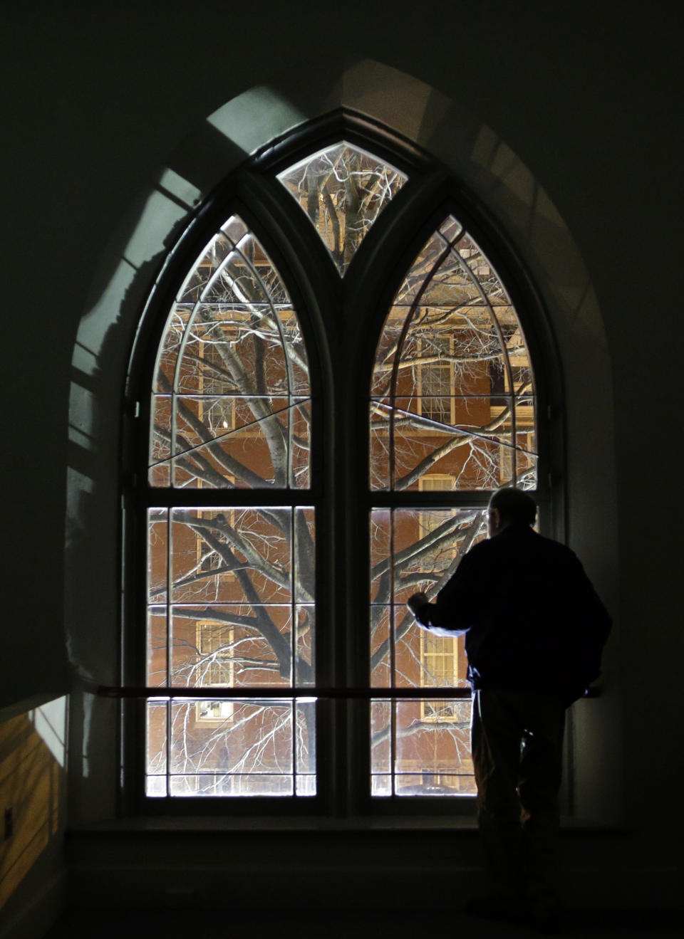 In this Jan. 15, 2013 photo, Jeff Jerome looks out of a window in Westminster Hall, which overlooks the cemetery that is home to Edgar Allan Poe's grave, in Baltimore. For years, Jerome watched as a mysterious man known as the Poe Toaster left three roses and an unfinished bottle of cognac at Poe’s grave every year on the legendary writer’s birthday. His identity is a great modern mystery, and just as mysteriously, the tradition ended four years ago. (AP Photo/Patrick Semansky)