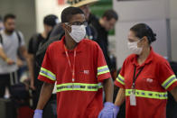 Airport employees wear masks as a precaution against the spread of the new coronavirus COVID-19 as they work at the Sao Paulo International Airport in Sao Paulo, Brazil, Wednesday, Feb. 26, 2020. (AP Photo/Andre Penner)
