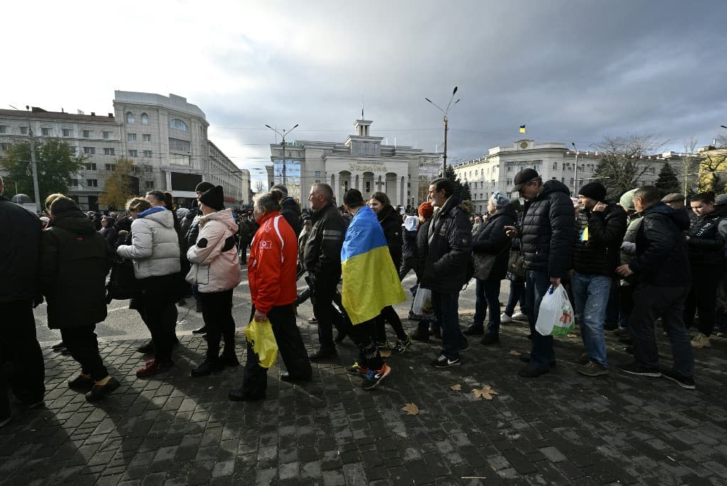 Des habitants font la queue pour la distribution de fournitures d'aide dans le centre de Kherson, le 19 novembre 2022, dans le contexte de l'invasion de l'Ukraine par la Russie. - GENYA SAVILOV / AFP