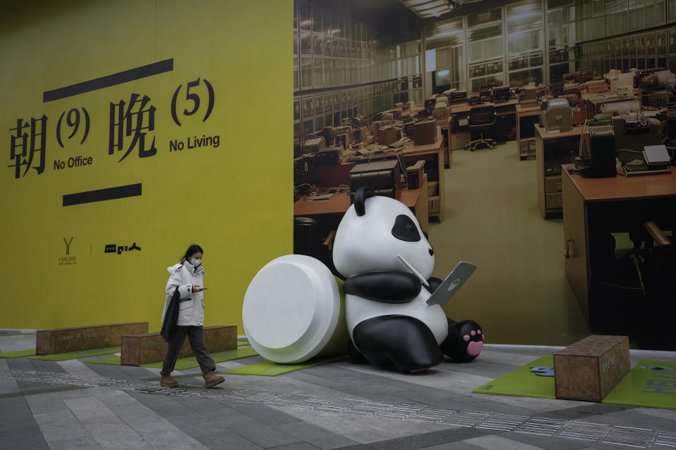 A woman walks by a sculpture depicting a working panda near a billboard promoting office space on a vacant lot of a commercial office building in Chengdu in southwestern China's Sichuan Province on Feb. 27, 2024. One burning issue dominates as the 2024 session of China's legislature gets underway this week: the economy. The National People's Congress annual meeting, which opens Tuesday, is being closely watched for any signals on what the ruling Communist Party might do to re-energize an economy that is sagging under the weight of expanded government controls and the bursting of a real-estate bubble. (AP Photo/Andy Wong)