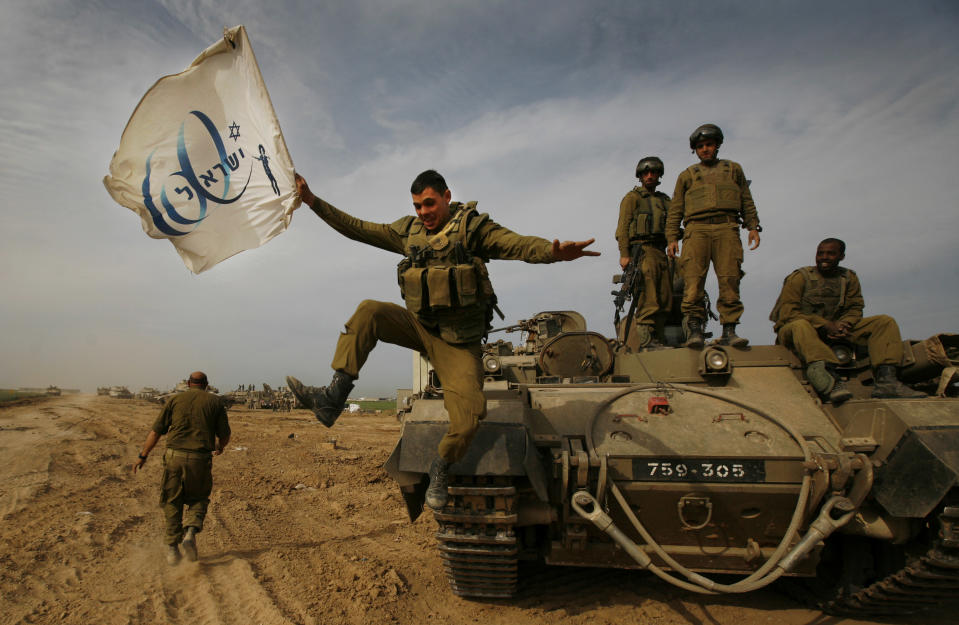 FILE - In this Friday, Jan. 16, 2009 file photo made by Associated Press photographer Anja Niedringhaus, an Israeli soldier jumps off an armored vehicle carrying a flag of Israel's 60th anniversary as he celebrates with his unit their return from the Gaza Strip on the Israeli side of the border. Niedringhaus, 48, an internationally acclaimed German photographer, was killed and AP reporter Kathy Gannon was wounded on Friday, April 4, 2014 when an Afghan policeman opened fire while they were sitting in their car in eastern Afghanistan. (AP Photo/Anja Niedringhaus, File)
