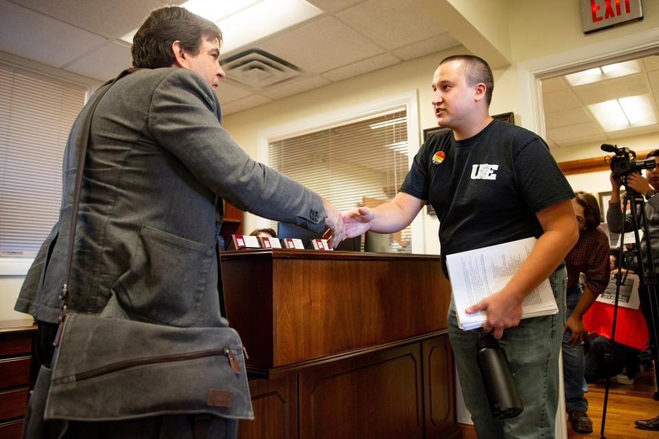 Bryson Stemock, a member of the New Mexico Grad Workers United, hands a proposed contract to an employee of the university during a union rally on Thursday, Oct. 27th, at New Mexico State University.
