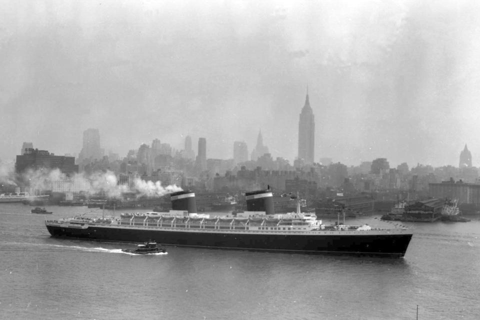 FILE - The S.S. United States glides down the Hudson River as it begins its first voyage to Europe from New York in view of the Manhattan skyline, including the Empire State Building on the center right, in this view from Hoboken, N.J., July 3, 1952. In a decision issued Friday, June 14, 2024, a federal judge said the historic ship that still holds the transatlantic speed record it set more than 70 years ago must leave its berth in Philadelphia by Sept. 12. (AP Photo/Jack Harris, File)