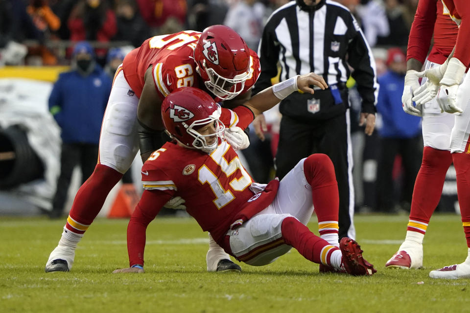 Kansas City Chiefs quarterback Patrick Mahomes (15) is helped up by teammate Trey Smith (65) after being knocked down during the first half of an NFL football game against the Cincinnati Bengals Sunday, Dec. 31, 2023, in Kansas City, Mo. (AP Photo/Ed Zurga)
