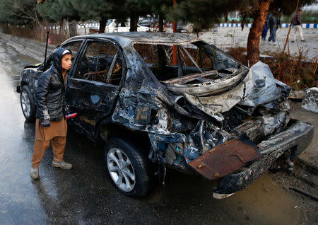 An Afghan boy looks at a destroyed vehicle after a suicide bomb attack in Kabul, Afghanistan November 16, 2017. REUTERS/Mohammad Ismail