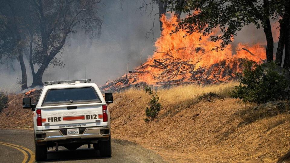 A Madera County Fire Department vehicle drives by burning vegetation as the Oak Fire moves through the area east of Mariposa on Saturday, July 23, 2022.