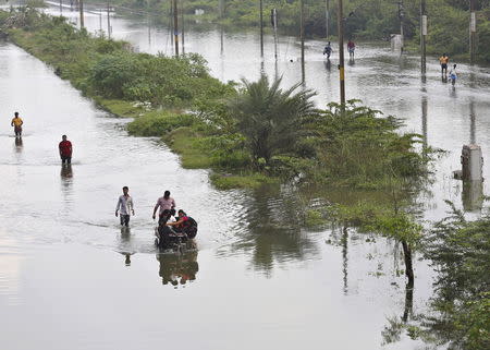 Displaced residents wade through a flooded street besides a flooded railway track in the flood-affected areas Chennai, India December 3, 2015. REUTERS/Anindito Mukherjee