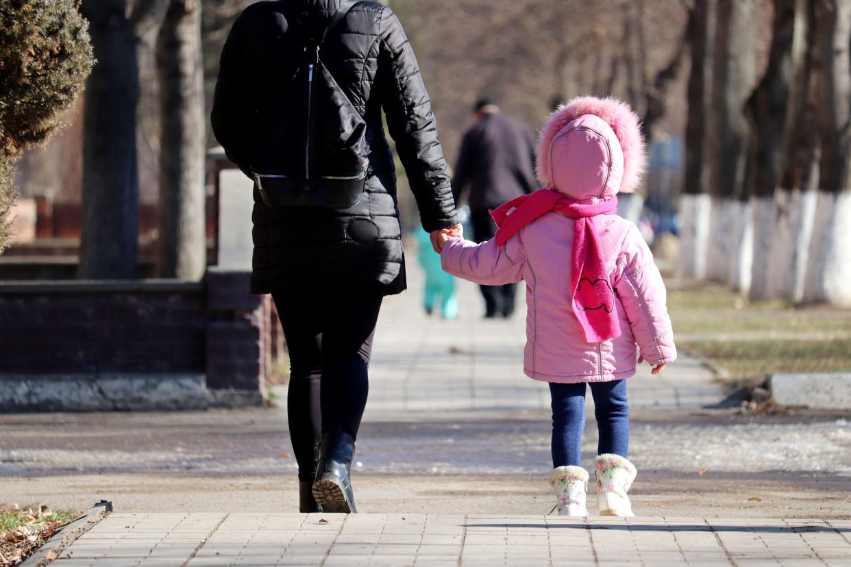 Mother and daughter walking down a street holding hands