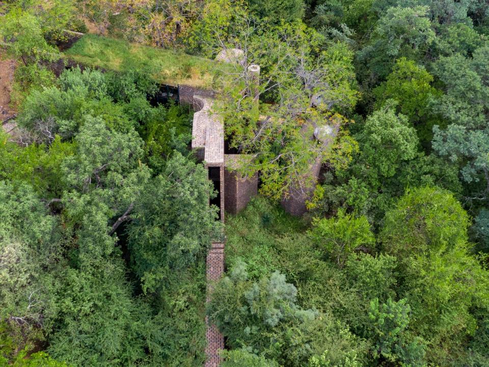 An exterior view of the House of the Big Arch in the trees