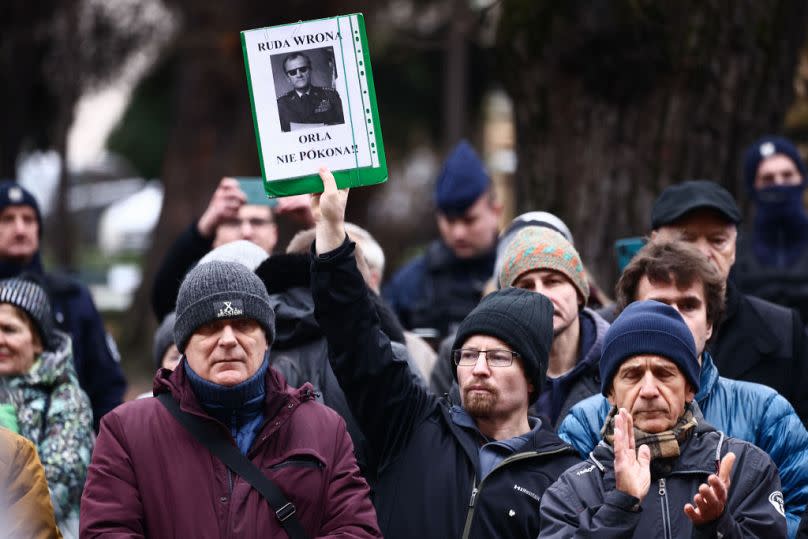 A man holds a banner with Tusk dressed as a communist-era head of state General Wojciech Jaruzelski during a protest against changes in publicly-owned media in Krakow