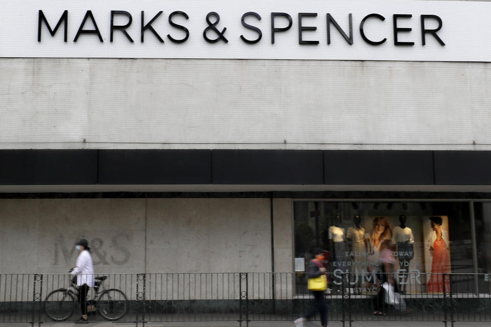 People pass a branch of Marks and Spencer in London, Tuesday, Aug. 18, 2020. Marks and Spencer has said it will cut 7,000 jobs over the next three months as the UK retailer overhauls its business in the latest sign of how the coronavirus pandemic has disrupted the high street. (AP Photo/Kirsty Wigglesworth)