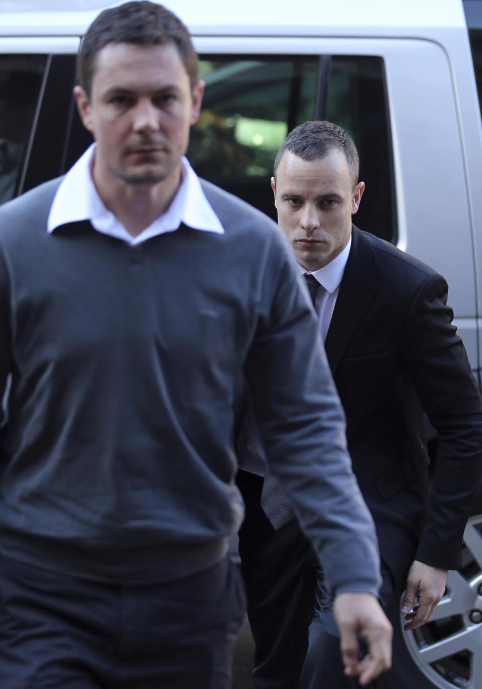 Oscar Pistorius, right, accompanied by an unidentified relative, arrives at the high court in Pretoria, South Africa, Monday, March 12, 2014. Pistorius is charged with murder for the shooting death of his girlfriend, Reeva Steenkamp, on Valentines Day in 2013. (AP Photo/Themba Hadebe)